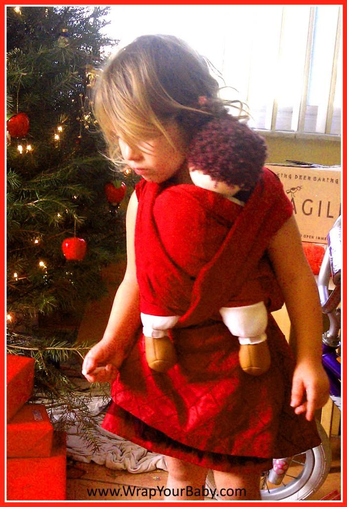 Toddler wearing baby in doll wrap at Christmas